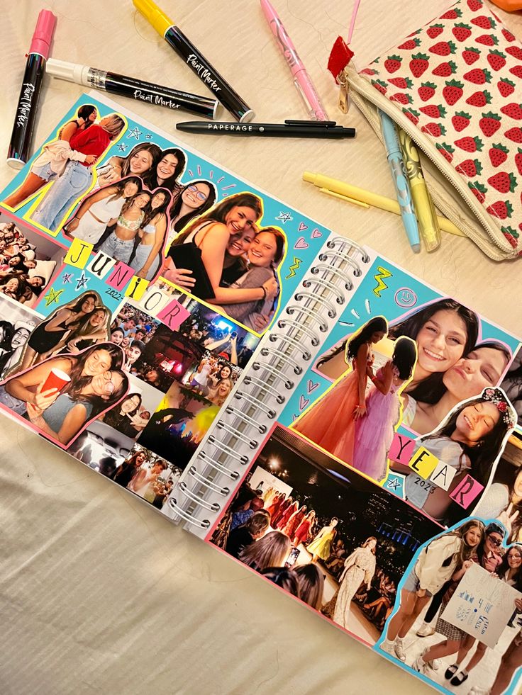 an open notebook with photos and pencils on it next to other items that include pens