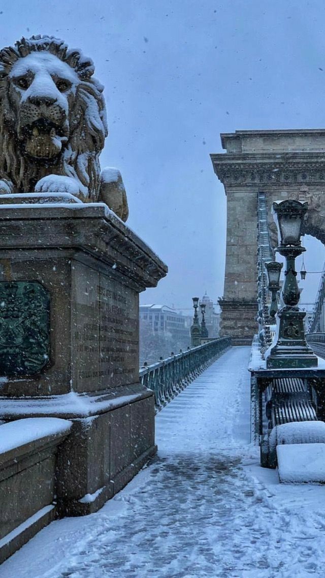 the bridge is covered in snow and has statues on it, along with benches that have been set up to look like lions