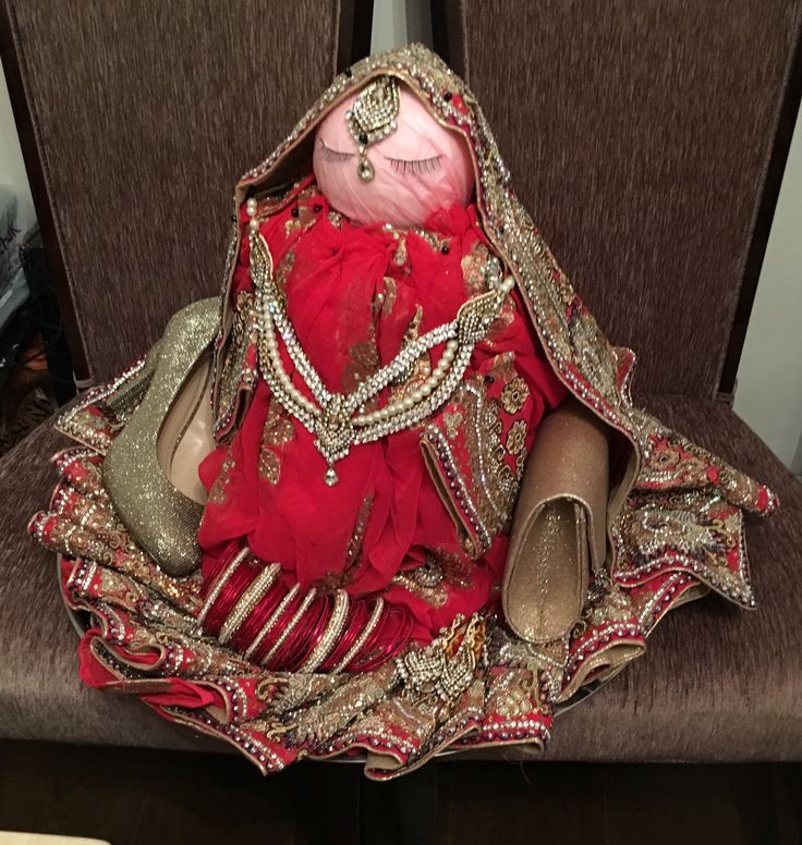 a doll dressed in red and gold sits on a chair