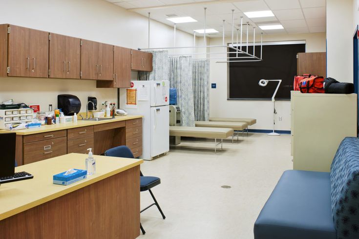 a hospital room filled with lots of furniture and medical supplies on the counter top next to a refrigerator