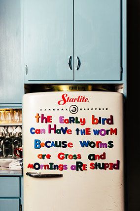 a refrigerator with words painted on it in a kitchen next to blue cabinets and cupboards