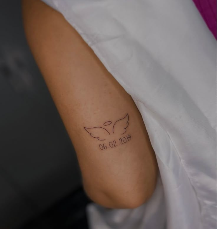 a woman's arm with a tattoo on it that reads 30 01 2009 and an angel