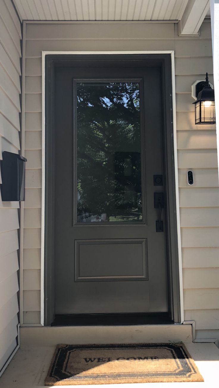 a gray front door with two lights on the side