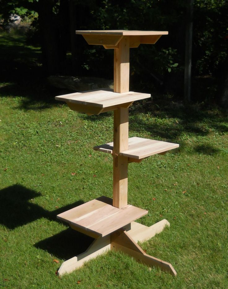 a three tiered wooden bird feeder in the grass