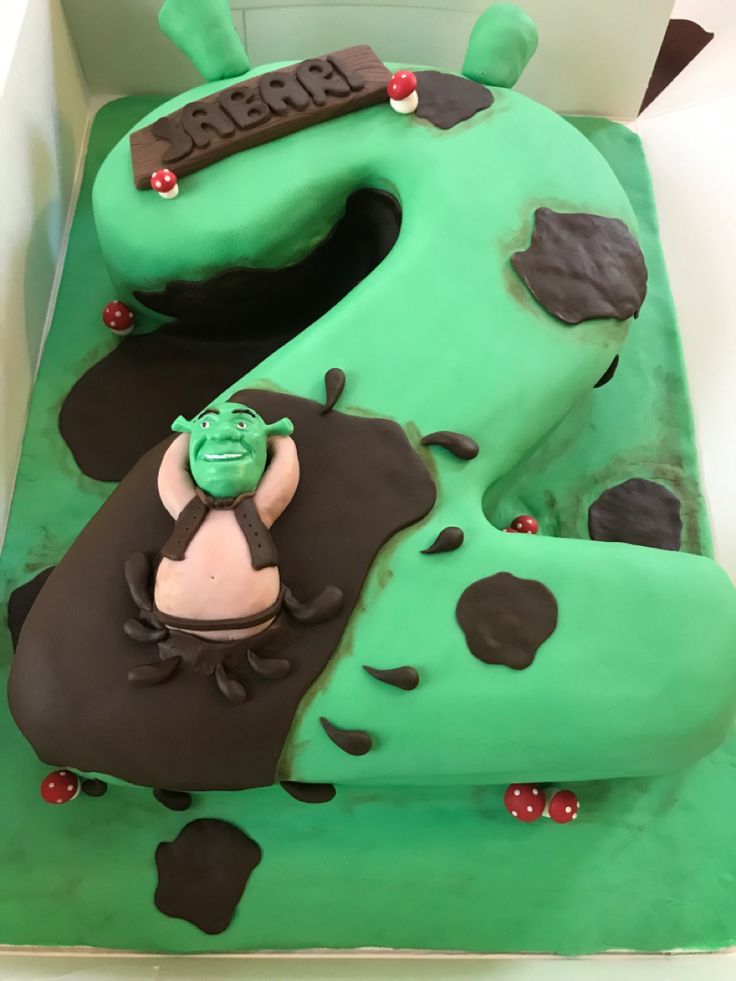 a green and black cake in the shape of a number six with a cartoon character on it