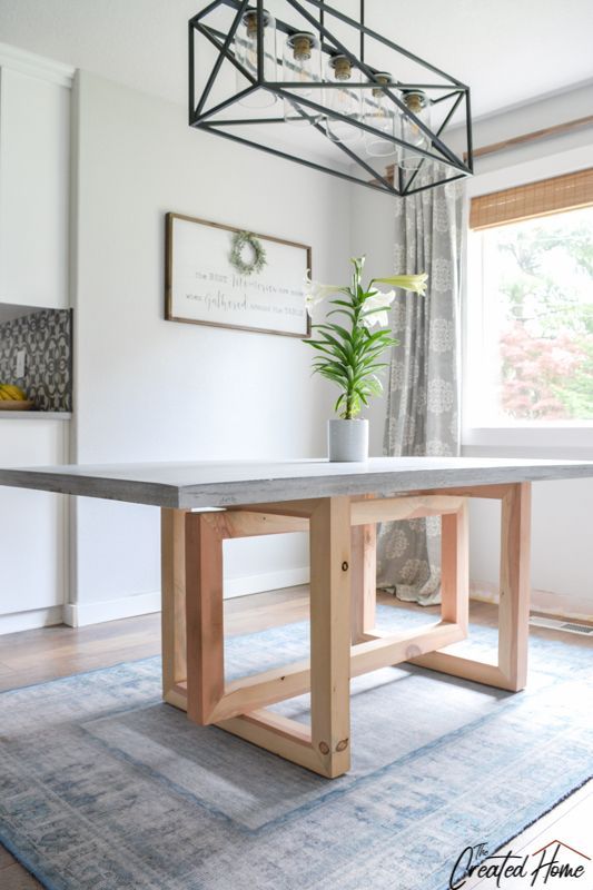 a dining room table with a potted plant sitting on it's end in front of a window