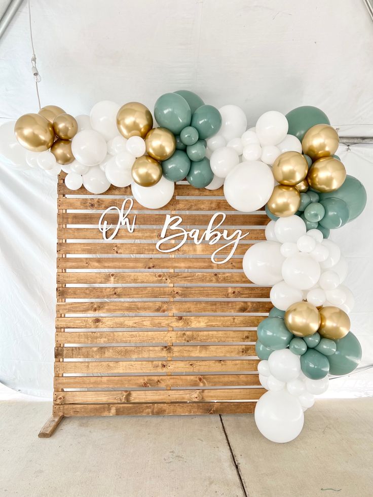 the balloon arch is decorated with gold, white and green balloons that say oh baby