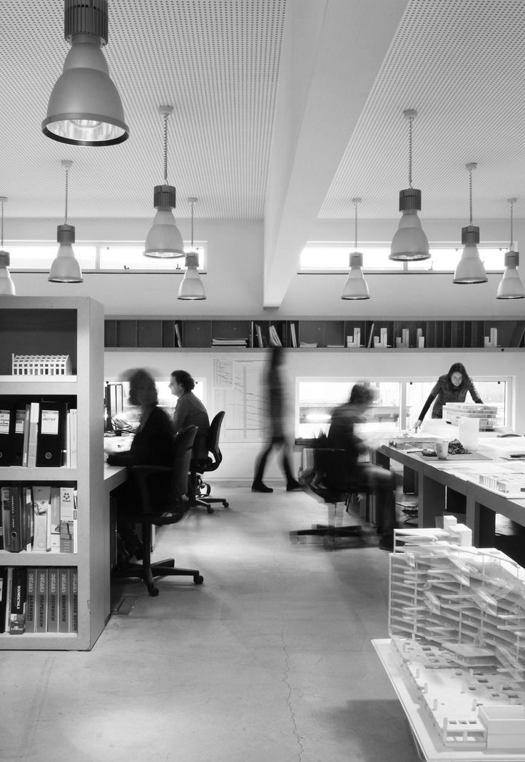 black and white photograph of people working at desks in an open area with bookshelves