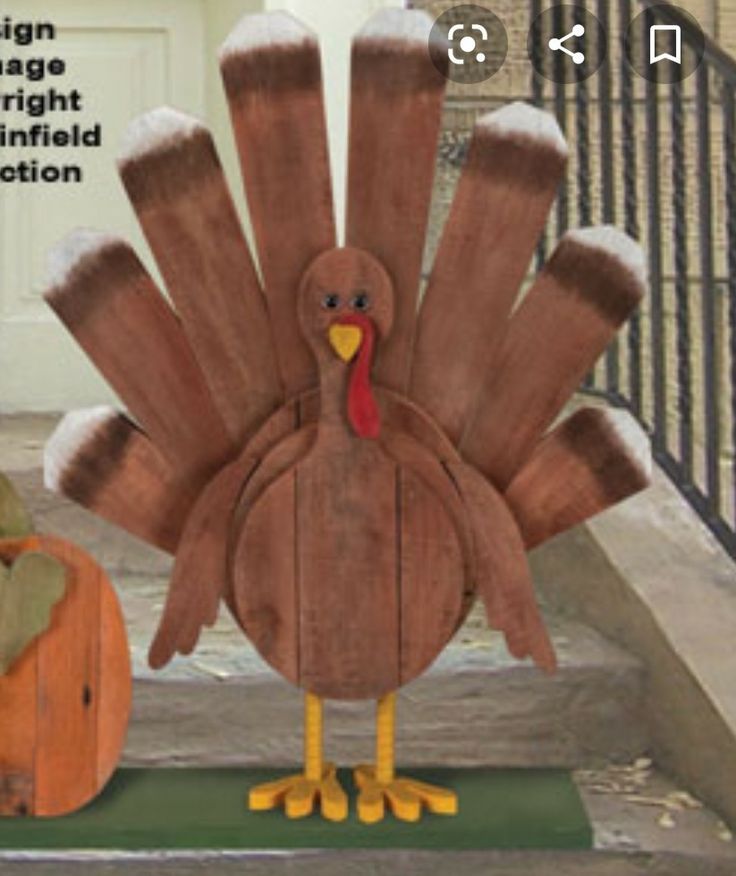 a wooden turkey standing next to a pumpkin on the steps in front of a house