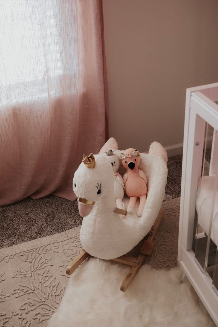 two stuffed animals are sitting in a rocking chair next to a baby crib and window