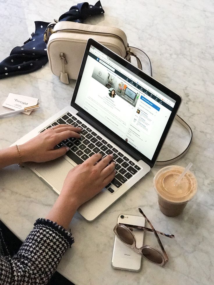 a woman sitting at a table with a laptop computer on her lap and coffee in front of her