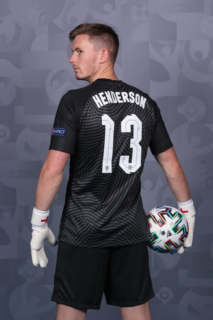 the soccer player is holding his ball and wearing white gloves with one hand on his hip