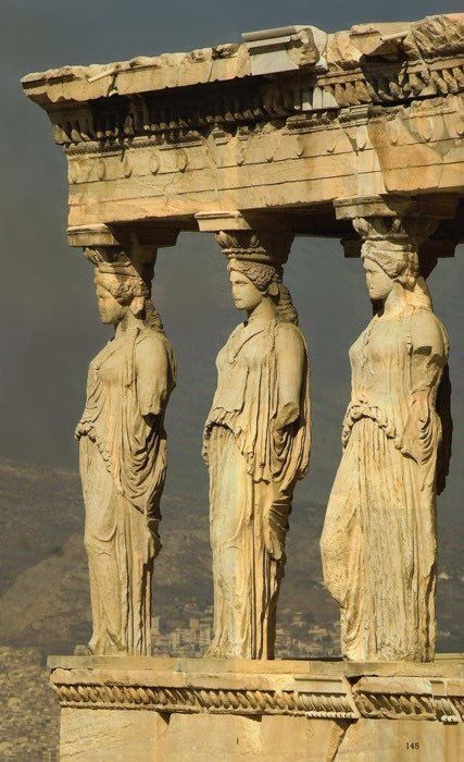 the four statues are standing next to each other on top of a stone structure with mountains in the background