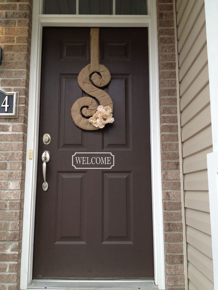 a door with a snake on it and a house number sign above the front door