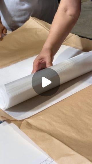 a person is wrapping up some paper on top of a cardboard box and making something