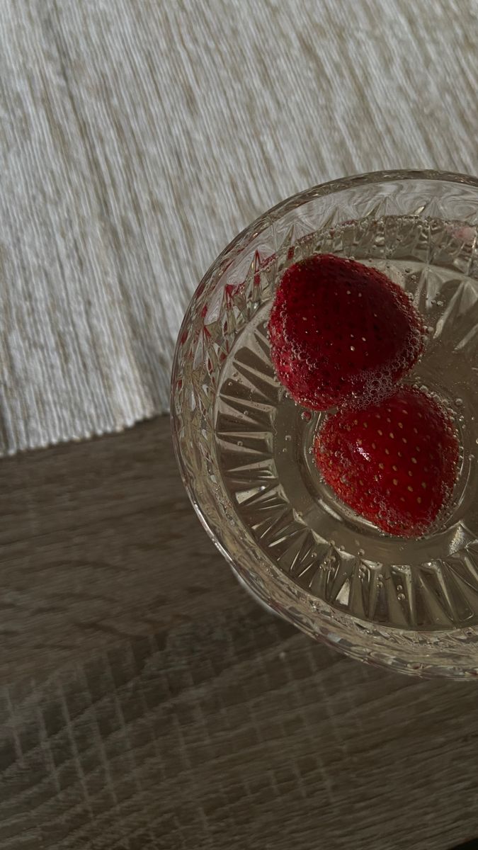 two strawberries in a glass bowl on a wooden table