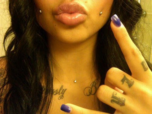 a woman with tattoos holding her finger up to the camera