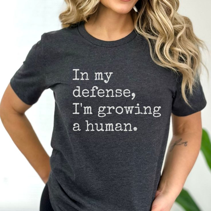 a woman wearing a t - shirt that says i'm my defense, i'm growing a human