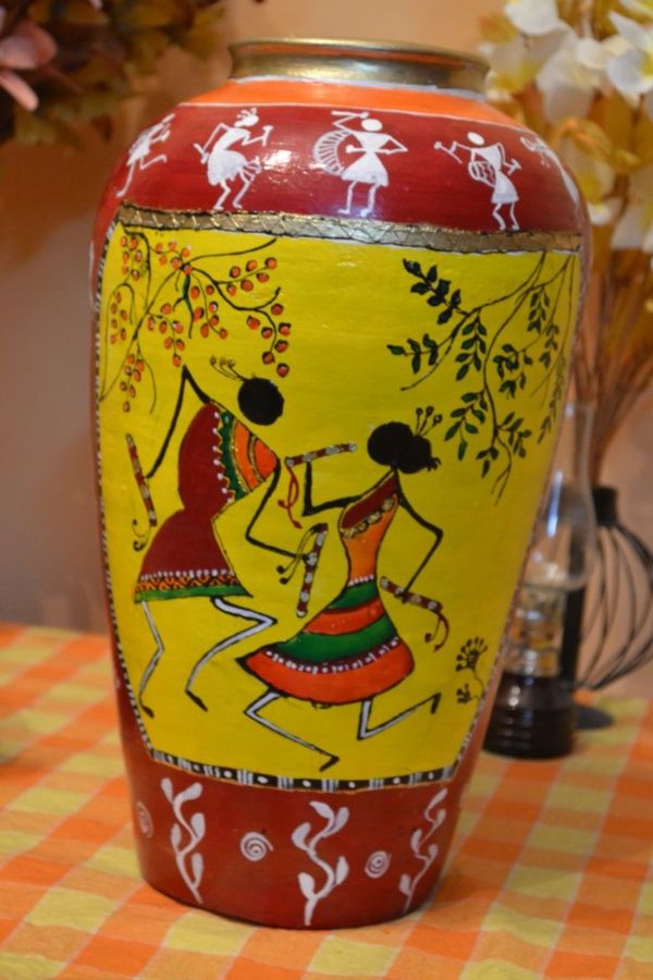 a yellow vase with red and white designs on it sitting on a checkered table cloth