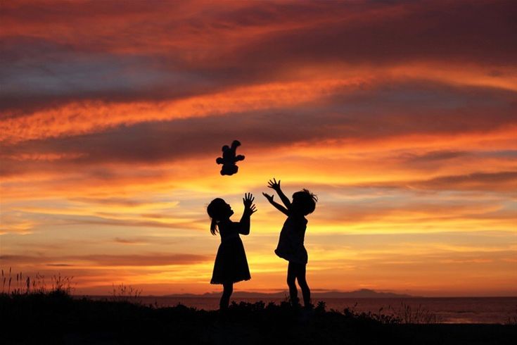 two children are playing with a bird at sunset