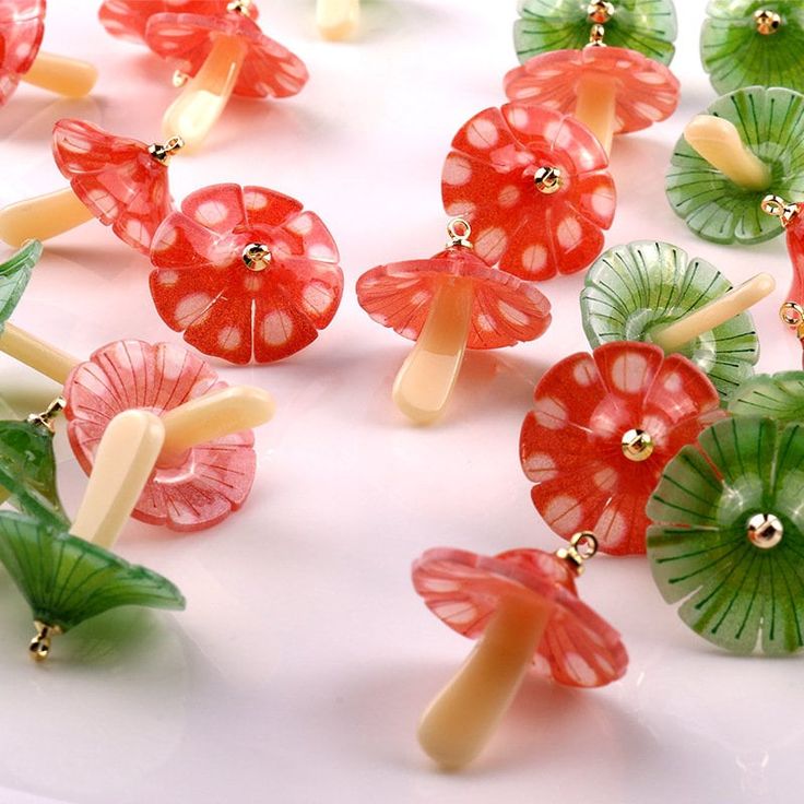 many small red and green flowers on a white surface with gold trim around the petals