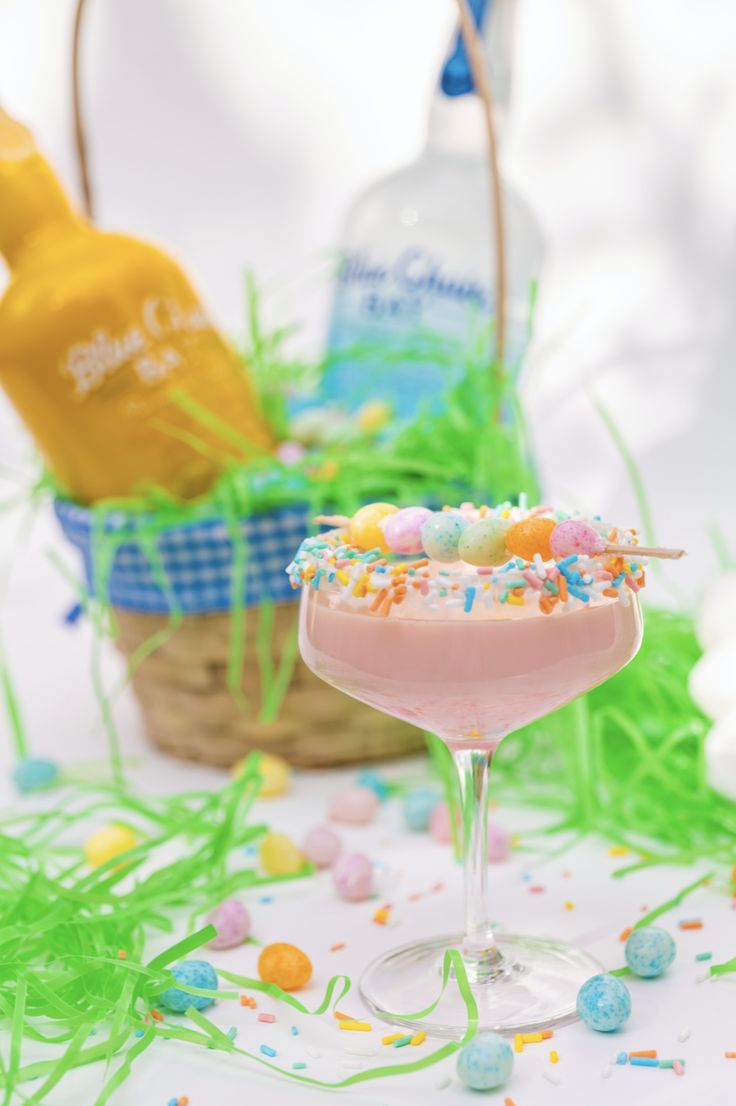 a pink drink with sprinkles in a glass next to an easter basket