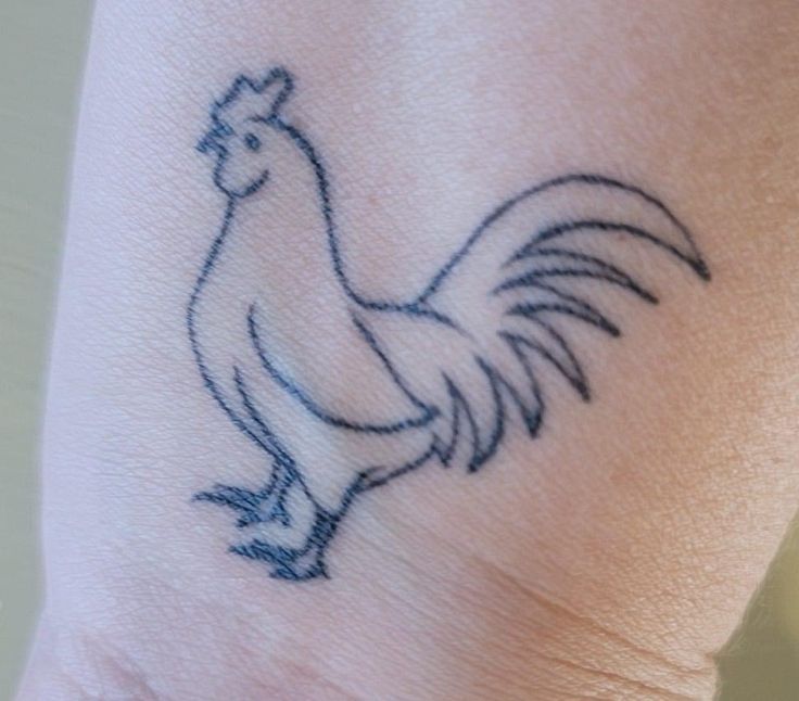 a small tattoo on the wrist of a woman's arm with a rooster drawn on it