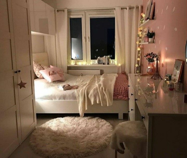 a bedroom with pink walls, white furniture and lights on the window sills