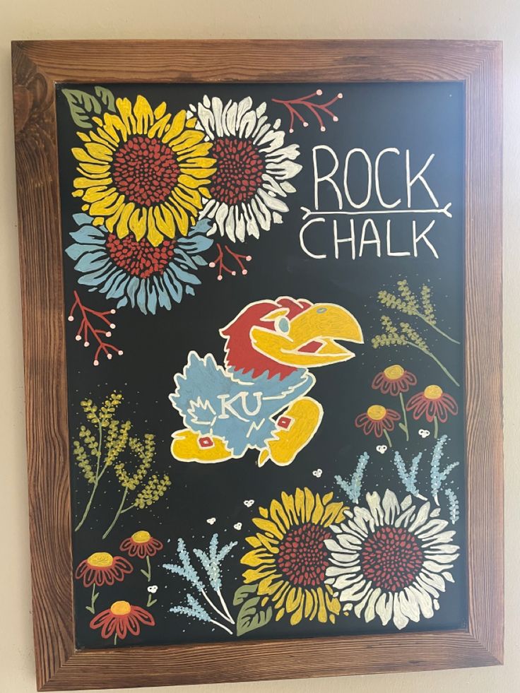 a painting on the wall with flowers and words written in chalkboard style writing that reads rock chalk