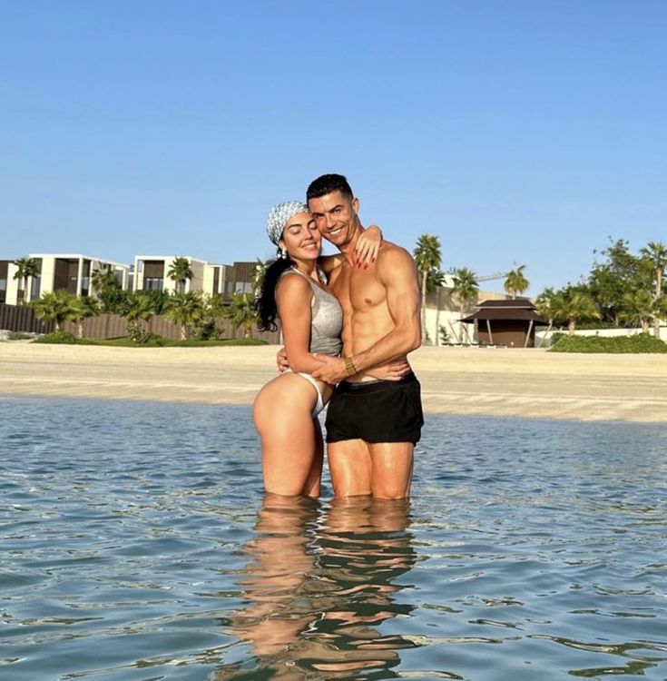 a man and woman are standing in the water near each other, posing for a photo