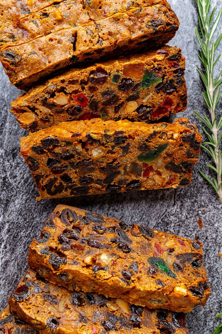 several slices of fruit and nut bread on a gray surface with rosemary sprigs