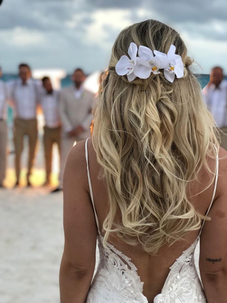 the back of a woman's head with white flowers in her hair and other people standing around