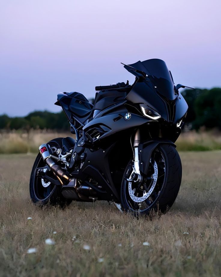 a black motorcycle parked on top of a dry grass field