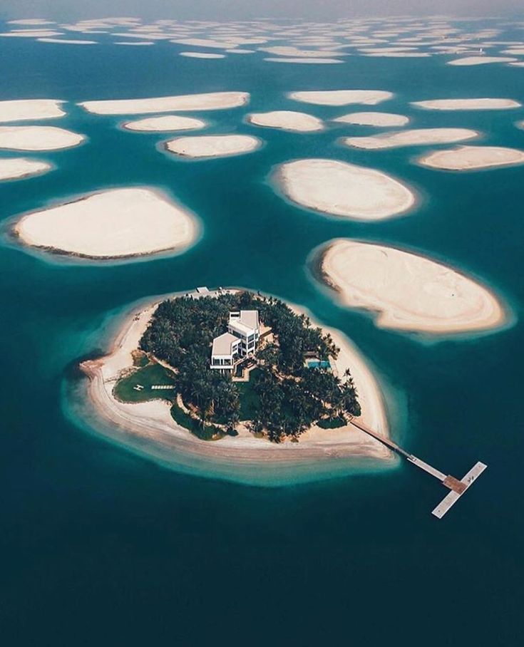 an island in the middle of water surrounded by small white islands with houses on them