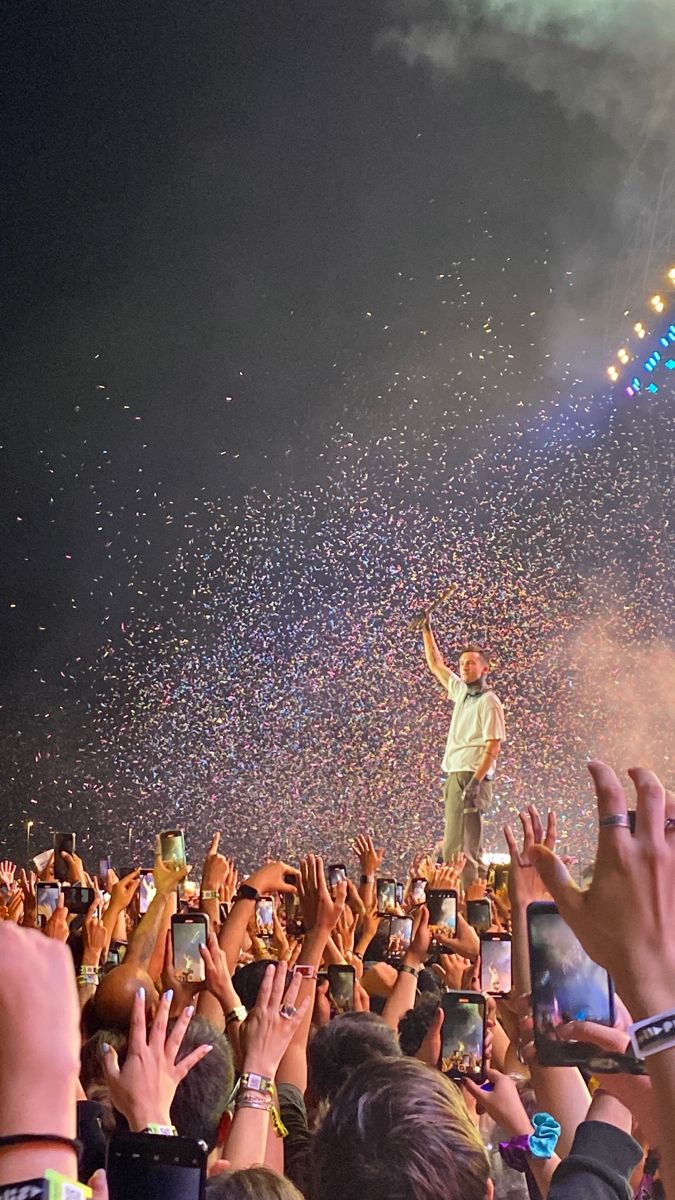 a man standing on top of a stage surrounded by confetti as people watch