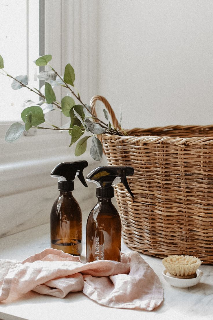 two brown bottles with sprayers next to a wicker basket on a countertop