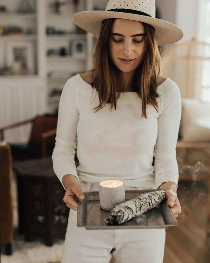 a woman wearing a hat holding a tray with a candle in it