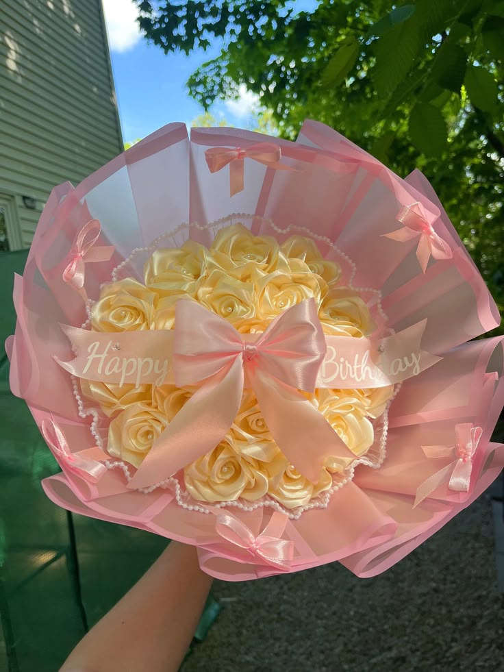 someone holding a bouquet of yellow roses with happy birthday written on the top in pink