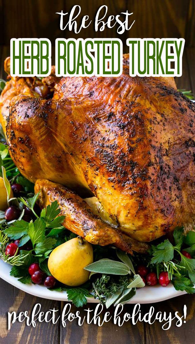 a roasted turkey on a platter with fresh herbs and lemons for the holiday