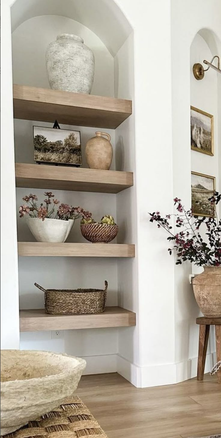 a living room filled with lots of shelves next to a wall mounted vase and potted plant