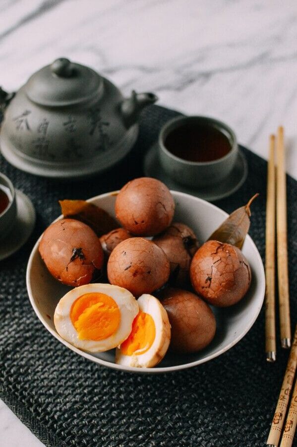 a bowl filled with boiled eggs next to chopsticks and teapot on a table