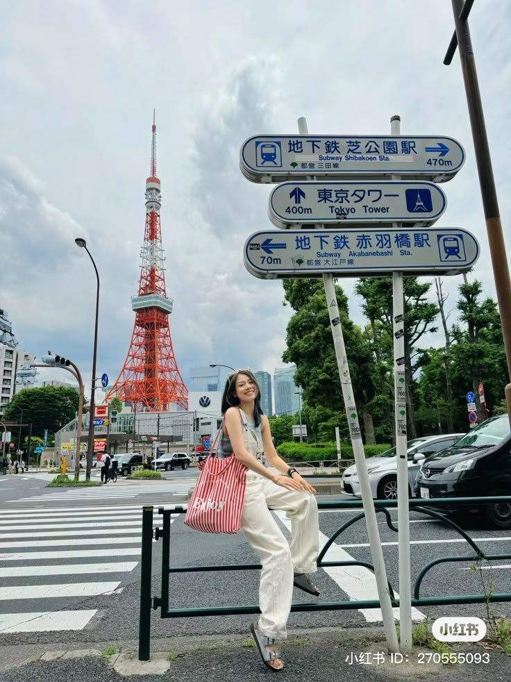 a woman sitting on top of a street sign next to a red and white eiffel tower