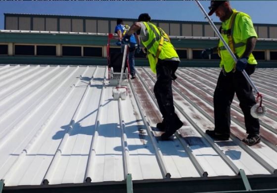 two men in yellow vests are cleaning the roof