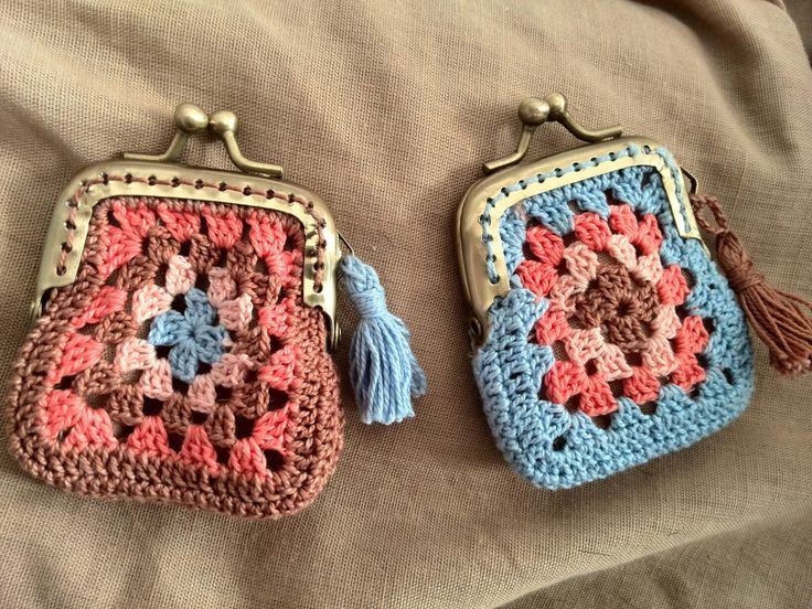 two crocheted purses sitting on top of a bed next to each other