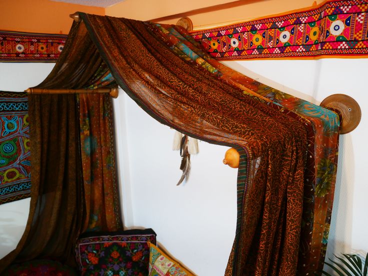 a canopy bed covered in colorful fabric and pillows