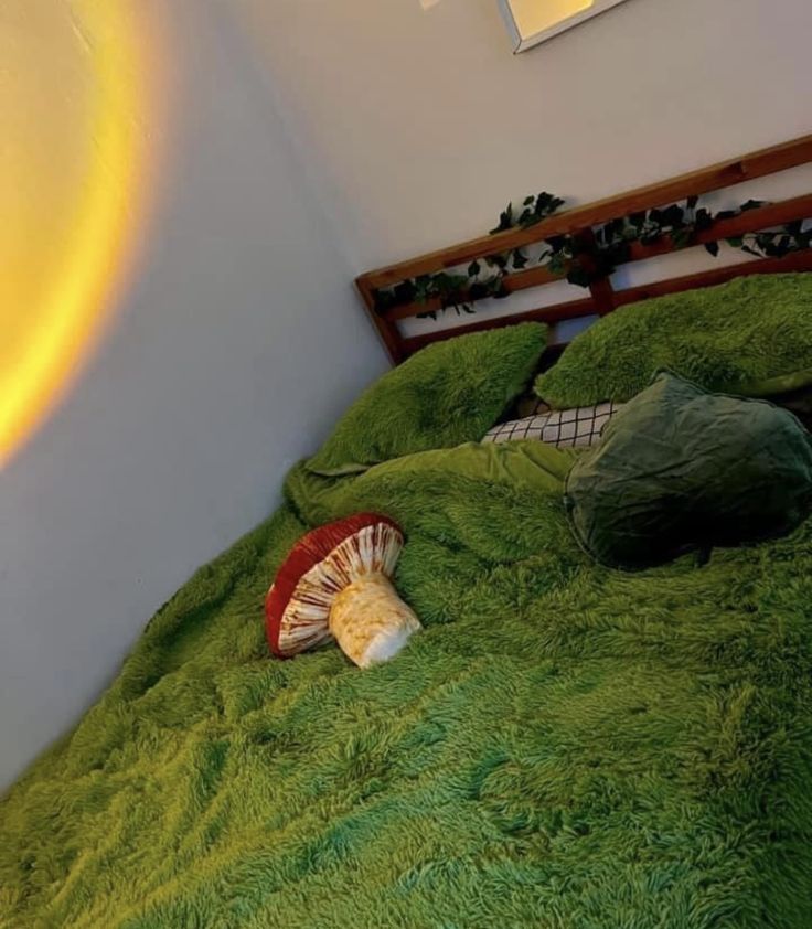 a bed with green sheets and pillows on top of it next to a wall light