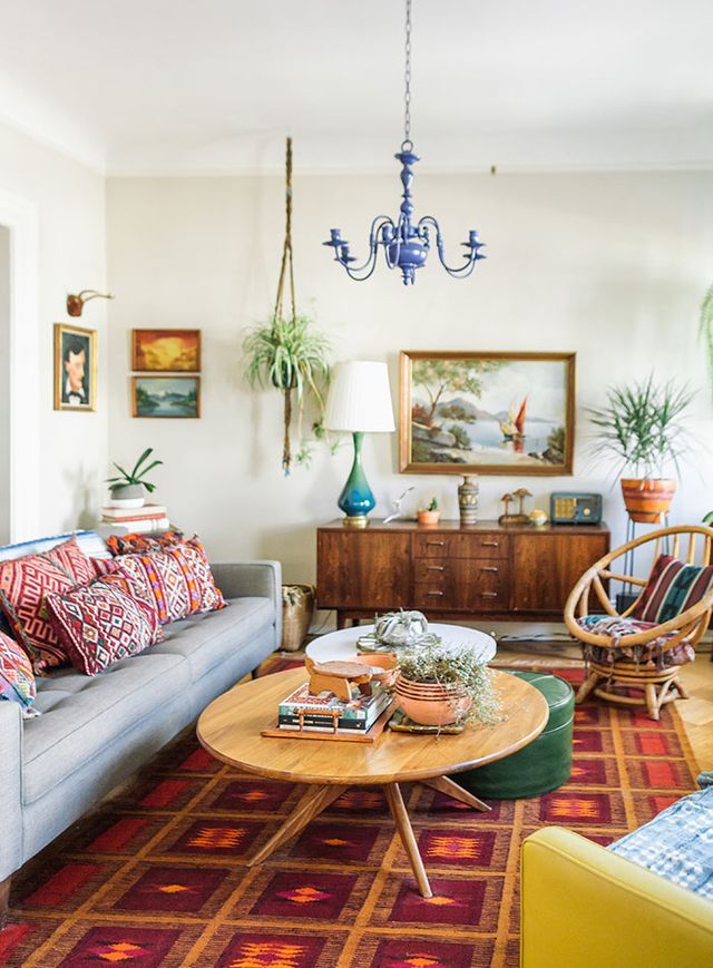 a living room filled with furniture and lots of plants on top of the tables in front of them