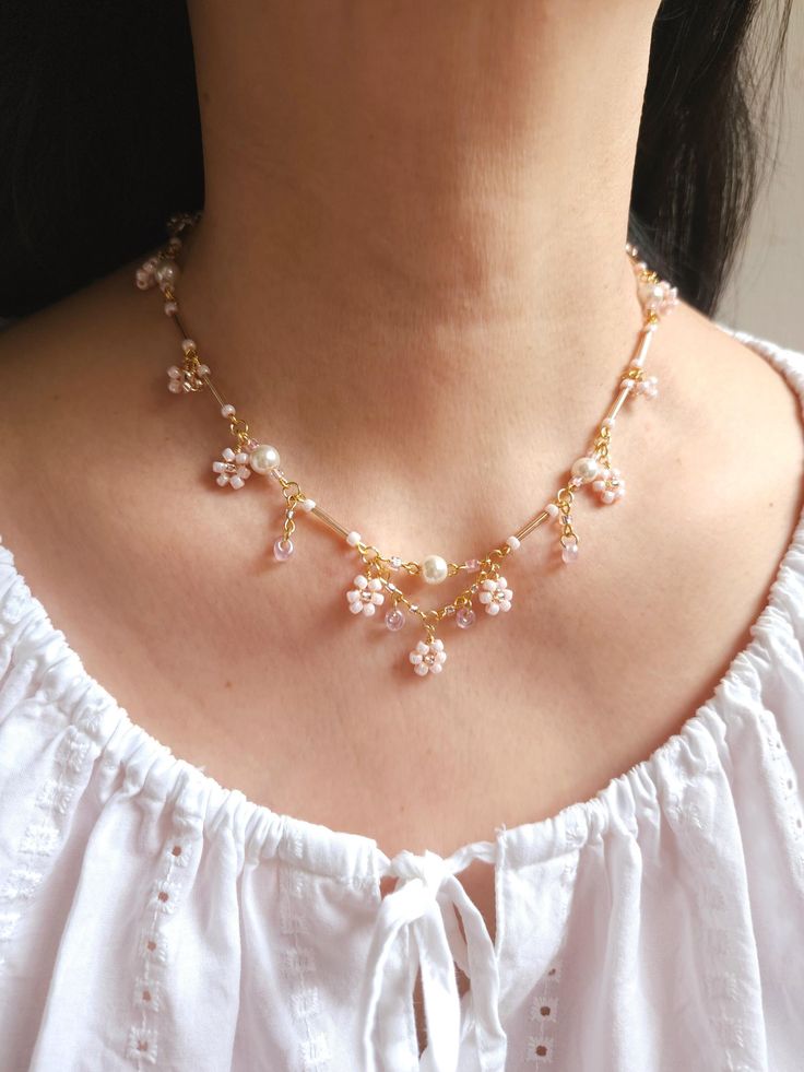 Introducing the Sweetspring Necklace, a girly and delicate flower-themed necklace, adorned with beaded light pink flowers, light pink pearls, and silvery pink bugle beads, it captures the essence of a blooming spring garden. This charming necklace is not only easy to wear but also perfect for everyday femininity. 🌸Handcrafted with glass pearls, glass bugle beads, glass seed beads, and gold-plated findings. 🌸All variations come with a 5cm extender. Cheap Trendy Flower Necklace, Luxury Flower-shaped Beaded Necklaces, Delicate Pearl Flower Necklace For Gift, Delicate Pearl Flower Necklace Gift, Pink Pearl Beaded Necklace Gift, Pink Pearl Beaded Necklace For Gift, Dainty Pink Beaded Necklaces For Gifts, Dainty Pink Beaded Necklace For Gift, Cute Pink Pearl Necklace