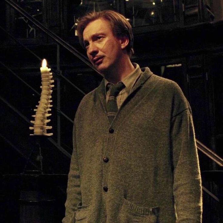 a man standing next to a lit candle in a dark room with stairs behind him