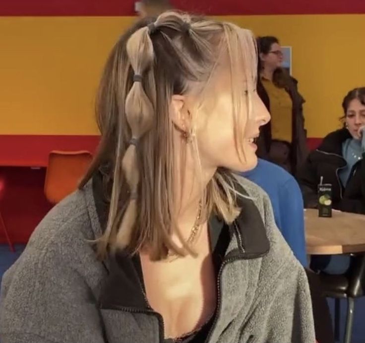 a woman with two braids in her hair sitting at a table and talking to someone